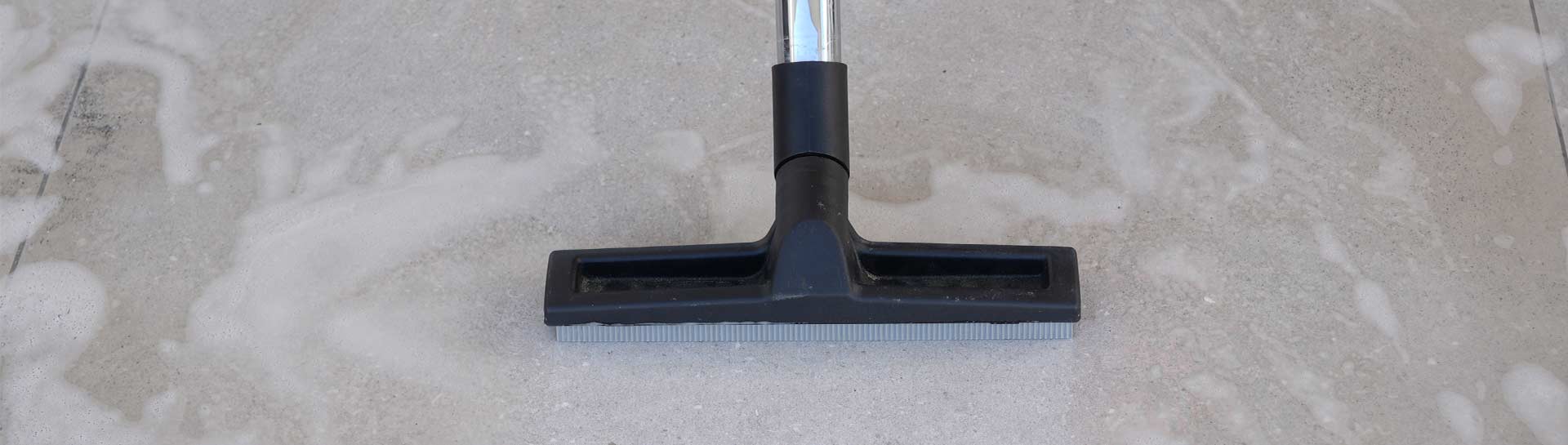 close up of a keeply employee deep cleaning of stone tile flooring with a wet vacuum