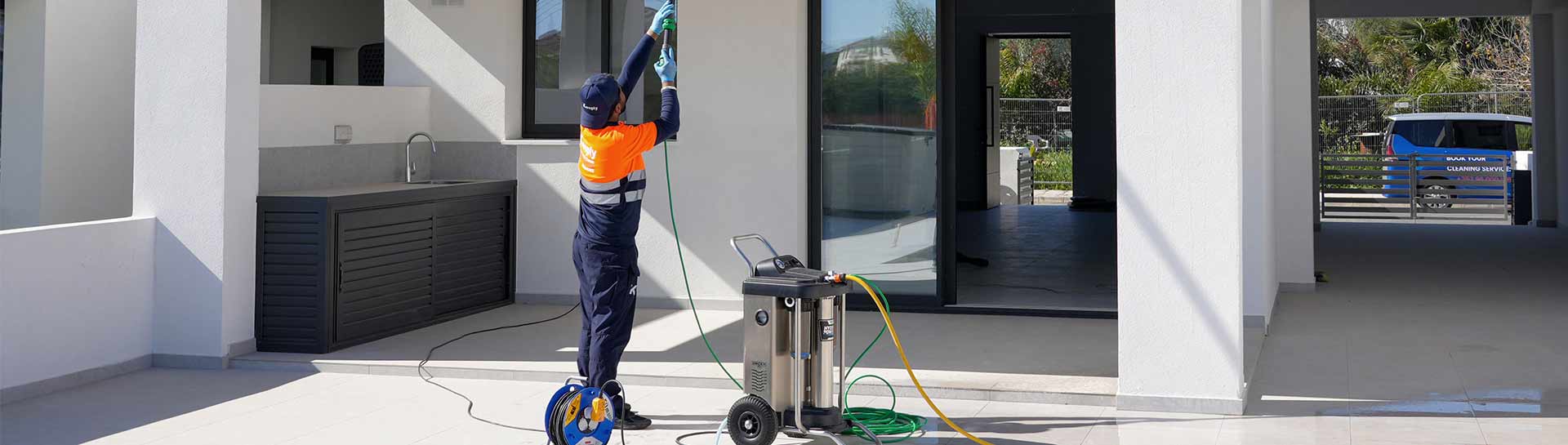 a closeup of a keeply employee using the ro water machine in order to clean outdoor glass of a house.