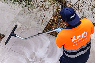 keeply employee in uniform cleaning the floor with the floor cleaning machine.