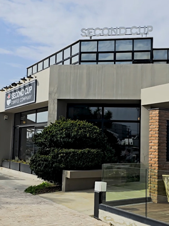 An exterior view of a modern 'Second Cup Coffee Company' building featuring clean and large glass windowsafter being cleaned by keeply.