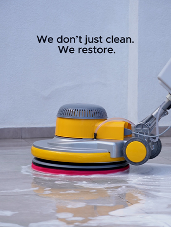 A professional floor scrubber machine being used by keeply to clean a tiled floor with white soapy foam, and 'We don't just clean. We restore' text above the machine.