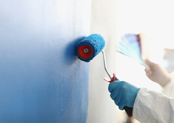close up of a keeply employee painting the walls of a house with a paint roller