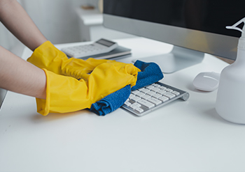 keeply employee cleaning the keyboard of a computer in an office