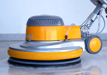 close up of a keeply employee cleaning the floor using a tile cleaning machine