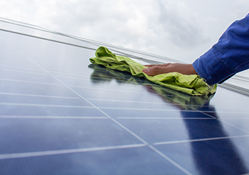 close up of keeply employee drying the solar panels after cleaning them
