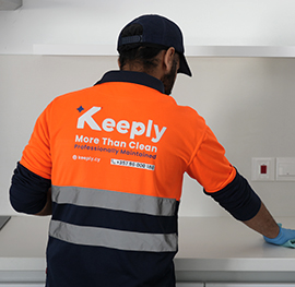 A keeply employee cleans a kitchen top using a cloth in a weekly cleaning service.