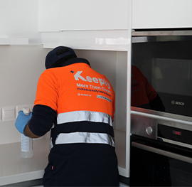 A keeply employee cleaning and wiping down a white kitchen countertop.