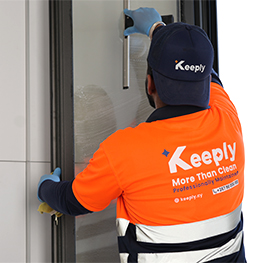 A Keeply employee using a squeegee to remove cleaning solution from a window.
