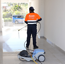 Keeply employee using a high-pressure water washer to clean a tiled floor