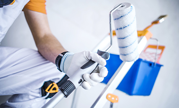 close up of keeply employee holding a paint roller to paint a wall.